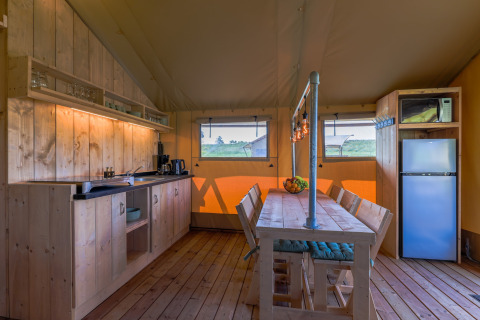 Interior of safari tent Villa Holiday Park IJsselhof 12 in the Netherlands with wooden furniture and kitchen.