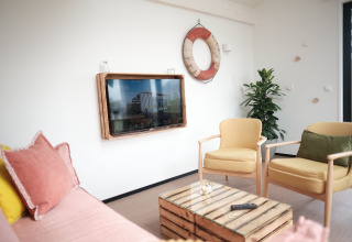 Heldere en gezellige leefruimte in Resort Callantsoog 2 in Nederland met kleurig meubilair en maritieme accenten.