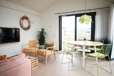 Lichte, moderne woonkamer in Resort Callantsoog 2 in Nederland met groene stoelen en grote ramen.