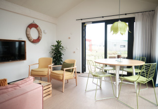 Lichte, moderne woonkamer in Resort Callantsoog 2 in Nederland met groene stoelen en grote ramen.