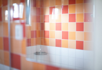 Brusebad med orange og røde kakler på væggen, spejling i glasset, Resort Callantsoog 2, Holland.