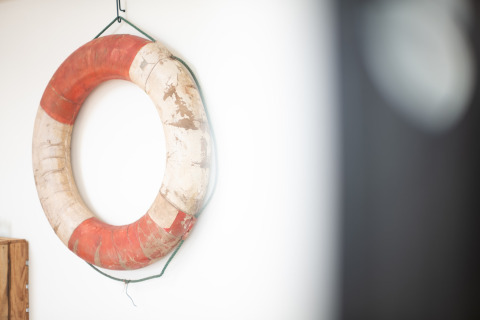 Een versleten reddingsboei met rode en witte vlakken hangt aan de muur bij Resort Callantsoog 2 in Nederland.