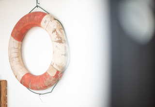 Een versleten reddingsboei met rode en witte vlakken hangt aan de muur bij Resort Callantsoog 2 in Nederland.