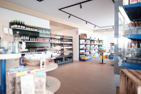 Interior view of a lodge grocery shop with well-lit shelves stocked with food products and wines.