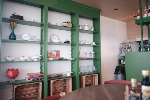 Inviting lodge interior with green shelves displaying dishes, decor items, board games, and mugs.