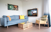 Sala moderna en la cabaña Resort Callantsoog 1, Países Bajos, con sofá azul, silla amarilla y TV de pared.
