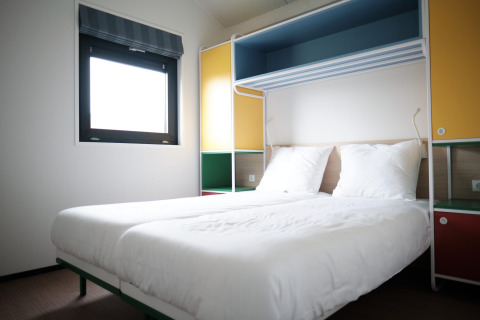 Modern lodge room at Resort Callantsoog 1 in the Netherlands with two single beds and colorful décor.