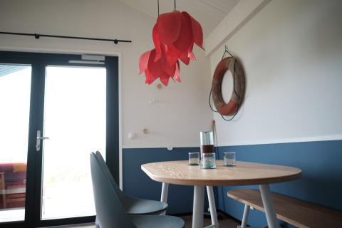 Cozy dining area with wooden table, chairs, and a lifebuoy on the wall at Resort Callantsoog 1, Netherlands.