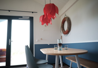 Acogedor comedor con mesa de madera, sillas y un salvavidas en la pared en Resort Callantsoog 1, Países Bajos.