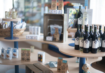 Boutique de lodge avec bouteilles de vin, produits régionaux et souvenirs sur des étagères en bois courbées.