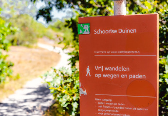 Panneau rouge aux Schoorlse Duinen indiquant les sentiers accessibles et les règles pour les visiteurs.