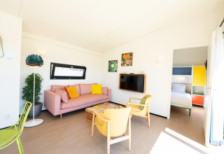 Lichte leefruimte met kleurrijk meubilair en slaapkamer in Resort Callantsoog 5, Nederland.