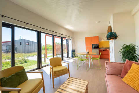 Heldere, moderne lodge in Resort Callantsoog 5 in Nederland met grote ramen en kleurrijke inrichting.