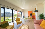 Lodge moderne et lumineux au Resort Callantsoog 5 aux Pays-Bas avec grandes fenêtres et mobilier coloré.
