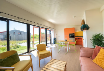 Lodge moderne et lumineux au Resort Callantsoog 5 aux Pays-Bas avec grandes fenêtres et mobilier coloré.