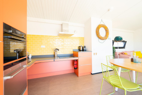 Lichte, kleurrijke keuken met oranje kasten en gele tegels in Resort Callantsoog 5 in Nederland.