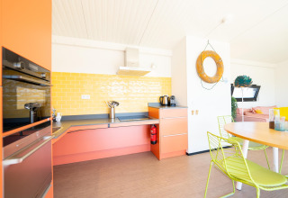 Lichte, kleurrijke keuken met oranje kasten en gele tegels in Resort Callantsoog 5 in Nederland.