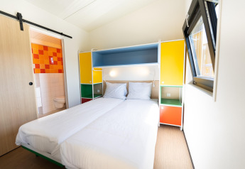 Chambre lumineuse au Resort Callantsoog 5 aux Pays-Bas avec lit double, placards colorés et salle de bain.