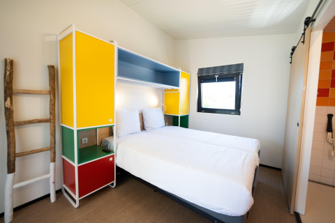 Moderne lodgekamer in Resort Callantsoog 5 in Nederland met kleurrijke meubels en twee bedden.