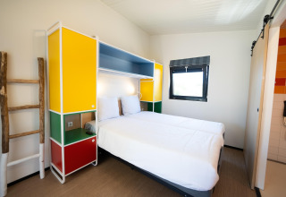 Moderne lodgekamer in Resort Callantsoog 5 in Nederland met kleurrijke meubels en twee bedden.