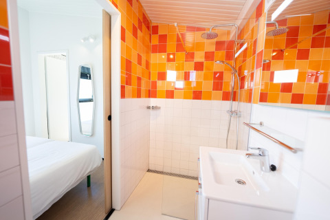 Moderne badkamer in Resort Callantsoog 5 in Nederland met opvallende oranje tegels en regendouche.