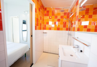 Moderne badkamer in Resort Callantsoog 5 in Nederland met opvallende oranje tegels en regendouche.