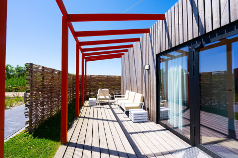 Terras bij Resort Callantsoog 5 in Nederland met moderne stoelen, houten terras en rode balken.