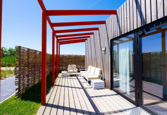 Terrasse du Resort Callantsoog 5 aux Pays-Bas avec fauteuils modernes, platelage bois et poutres rouges.