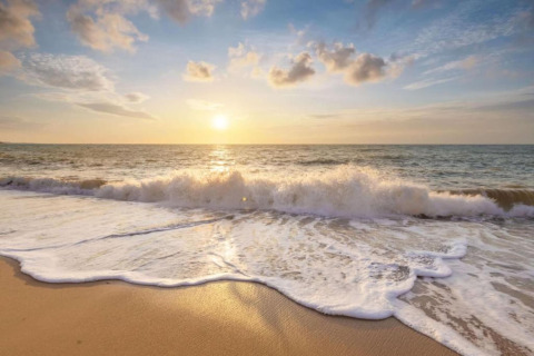 Zonsopgang aan het strand van Resort Callantsoog 5 in Nederland met golven en goudkleurig zand.