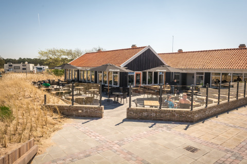 Terrasse extérieure du Holiday Park Loodsmansduin 1 aux Pays-Bas, avec sièges et vue sur les dunes.