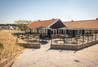 Außenterrasse des Holiday Park Loodsmansduin 1 in den Niederlanden mit Sitzbereichen und Dünenblick.