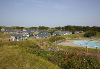 Holiday Park Loodsmansduin 1 in the Netherlands, featuring cabins, a swimming pool, and playground area.