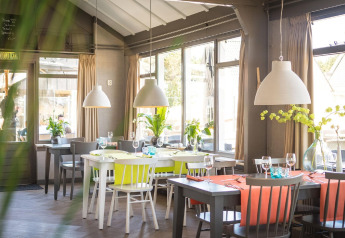 Dining area at Holiday Park «Loodsmansduin 1» in the Netherlands, featuring bright decor and large windows.
