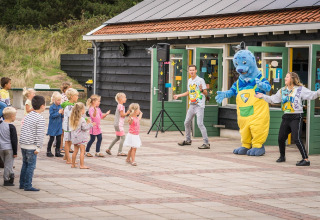 Bambini partecipano a giochi all'aperto con una mascotte al Holiday Park Loodsmansduin 1, Paesi Bassi.