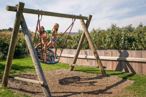 Due bambini giocano su un’altalena a nido nel parco giochi di Holiday Park Loodsmansduin nei Paesi Bassi.