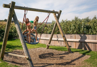 To børn leger på en stor redegynge på legepladsen ved Holiday Park Loodsmansduin i Holland.