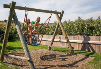 Two children play on a large nest swing at the playground in Holiday Park Loodsmansduin, Netherlands.