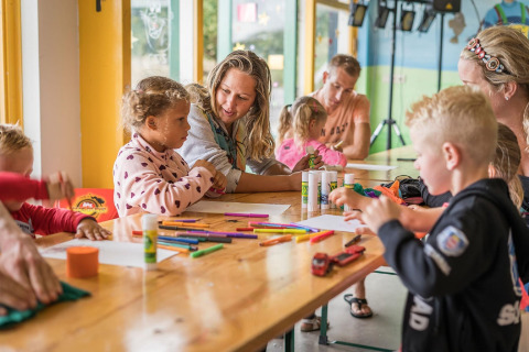 Kinder und Erwachsene basteln zusammen an einem Tisch im Holiday Park Loodsmansduin 1, Niederlande.