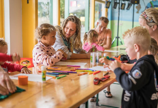 Enfants et adultes réalisent des bricolages sur une table au Holiday Park Loodsmansduin 1, Pays-Bas.