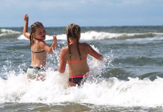 To børn leger i bølgerne ved stranden på Holiday Park «Loodsmansduin 1» i Holland.