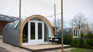 Et billede af De Ree en de Specht-podden med terrasse, udendørs siddepladser og flere pods bagved.