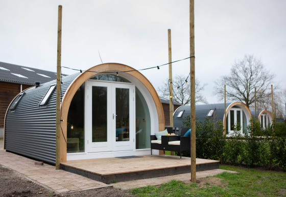 Et billede af De Ree en de Specht-podden med terrasse, udendørs siddepladser og flere pods bagved.