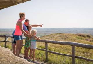 Familie blickt gemeinsam von der Holzterrasse im Holiday Park Loodsmansduin 1 in den Niederlanden.