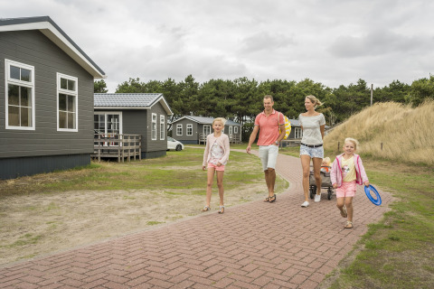 Una famiglia passeggia al Holiday Park «Loodsmansduin 1» nei Paesi Bassi, circondata da casette di legno.