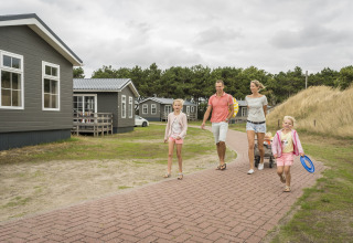 Une famille se promène sur un sentier au Holiday Park «Loodsmansduin 1» aux Pays-Bas, près de chalets.
