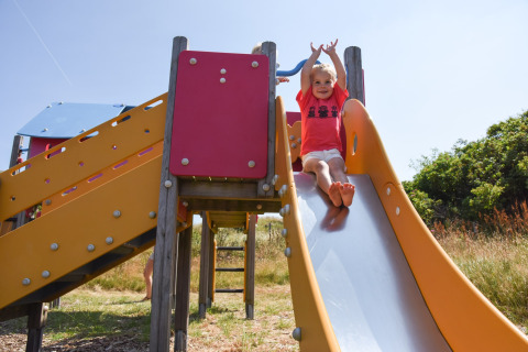 Bambino che scivola su uno scivolo colorato al Holiday Park Loodsmansduin 1 nei Paesi Bassi in una giornata di sole.