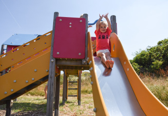 Child sliding down a colorful playground slide at Holiday Park Loodsmansduin 1 in the Netherlands.