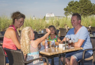 Eine Familie genießt eine Mahlzeit im Freien im Holiday Park Loodsmansduin 1 in den Niederlanden.
