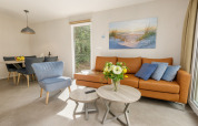 Modern lounge at Holiday Park Kijkduin 9, Netherlands, with leather sofa, blue armchair, and flowers.