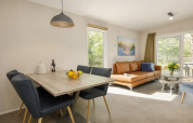 Modern living and dining area at Holiday Park «Kijkduin 9» in the Netherlands with large windows, cozy decor.